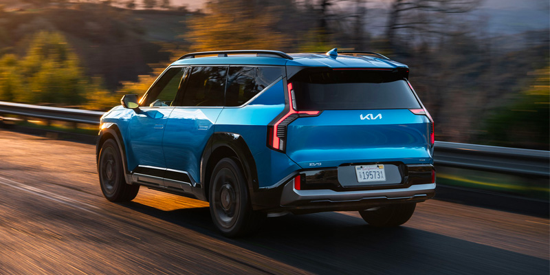 a blue 2025 Kia EV9 driving on a road