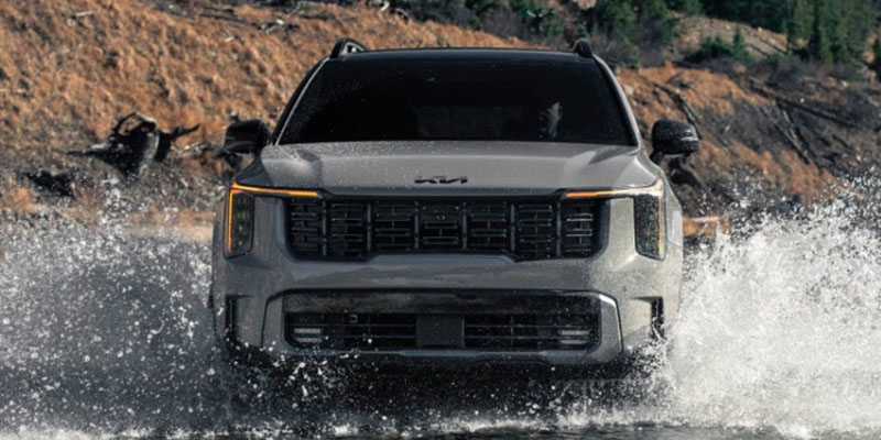 a 2025 Kia Sorento driving through a large puddle splashing water up